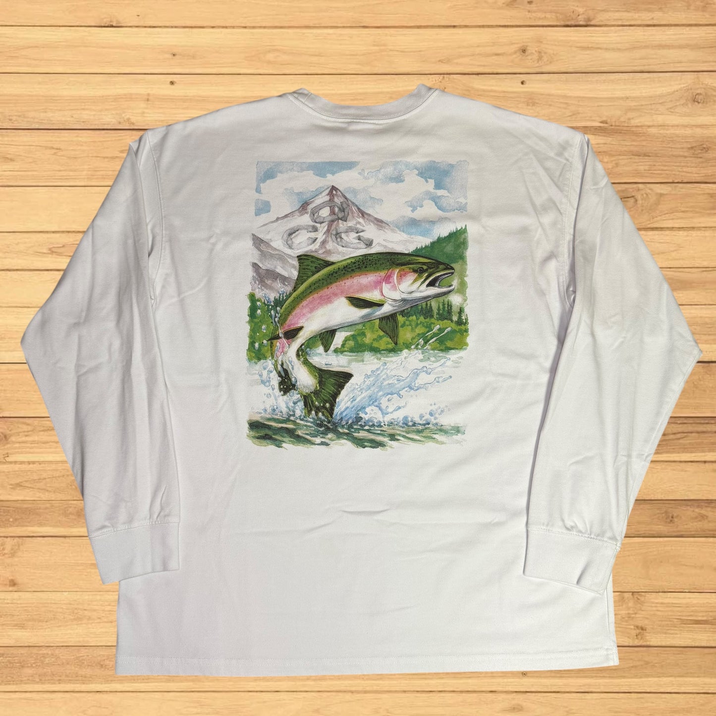 White long-sleeve shirt with a fish and mountain graphic on a wooden surface
