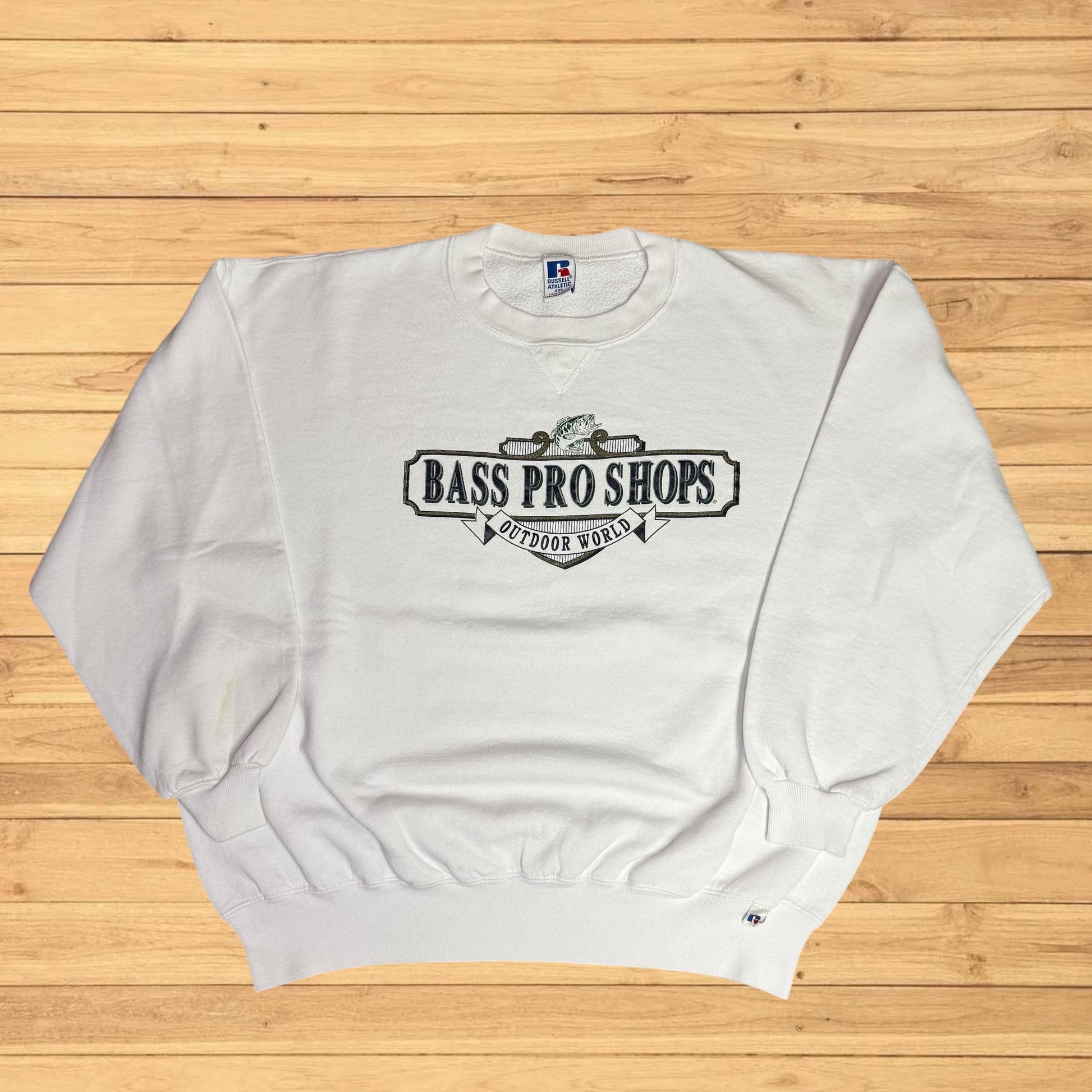 White sweatshirt with Bass Pro Shops logo on a wooden surface