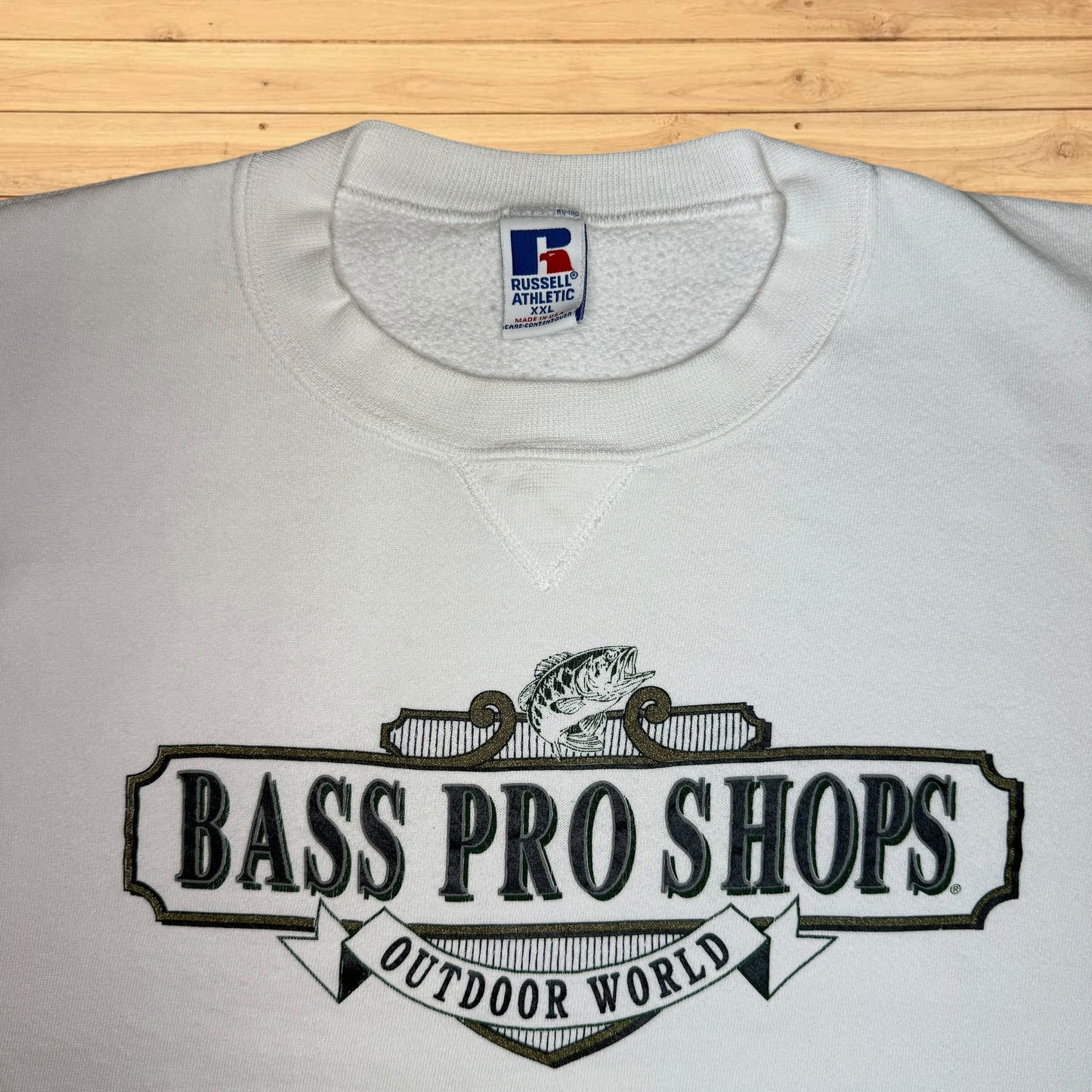 White sweatshirt with Bass Pro Shops logo on a wooden surface