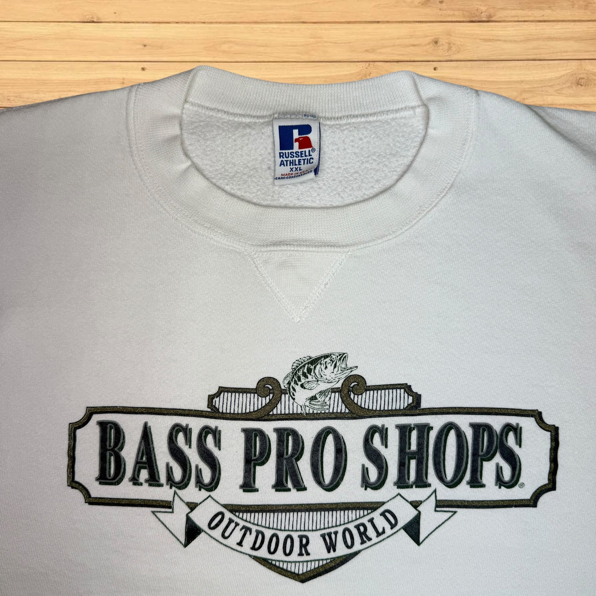 White sweatshirt with Bass Pro Shops logo on a wooden surface