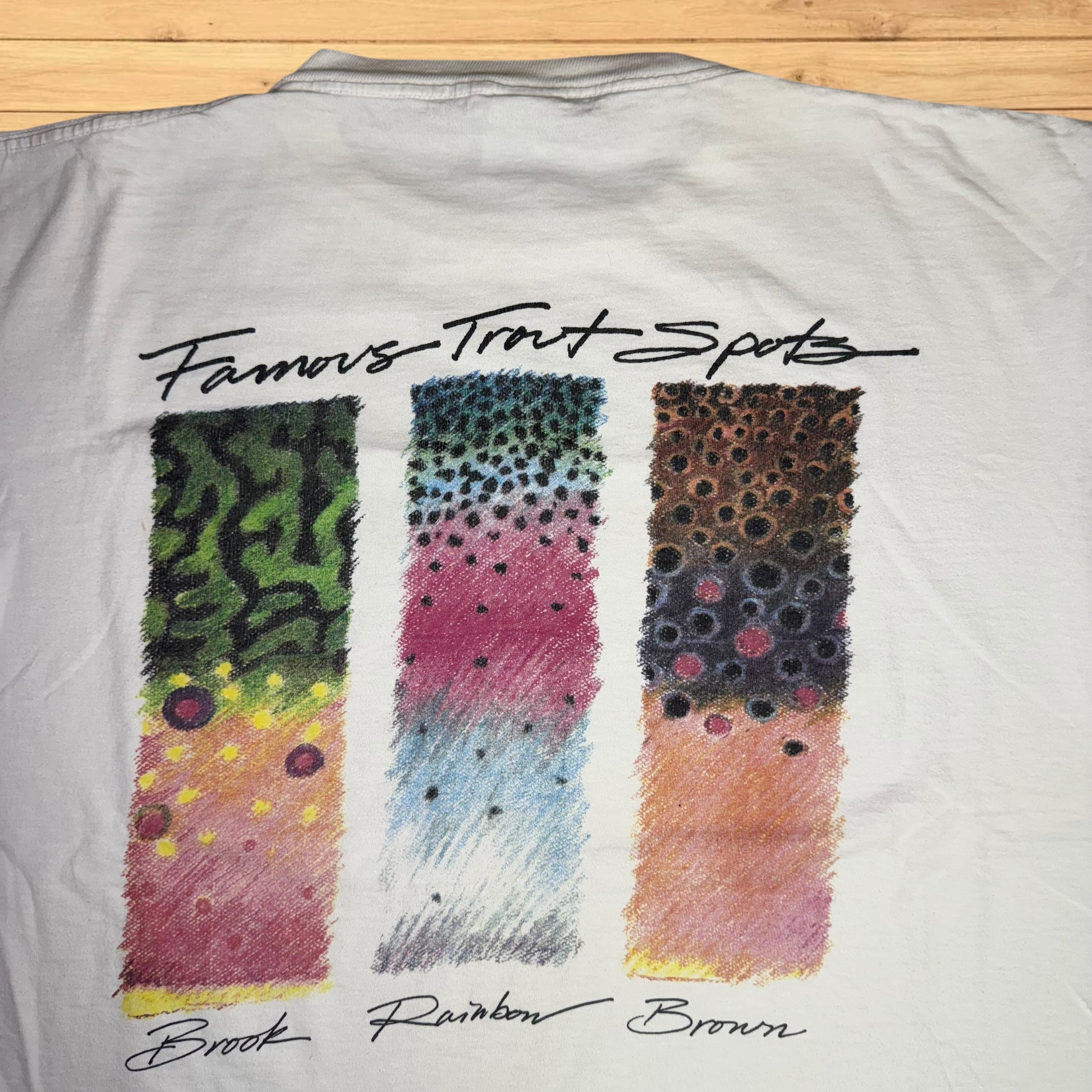 Gray shirt with colorful swatches labeled 'Brook', 'Rainbow', and 'Brown' on a wooden surface.