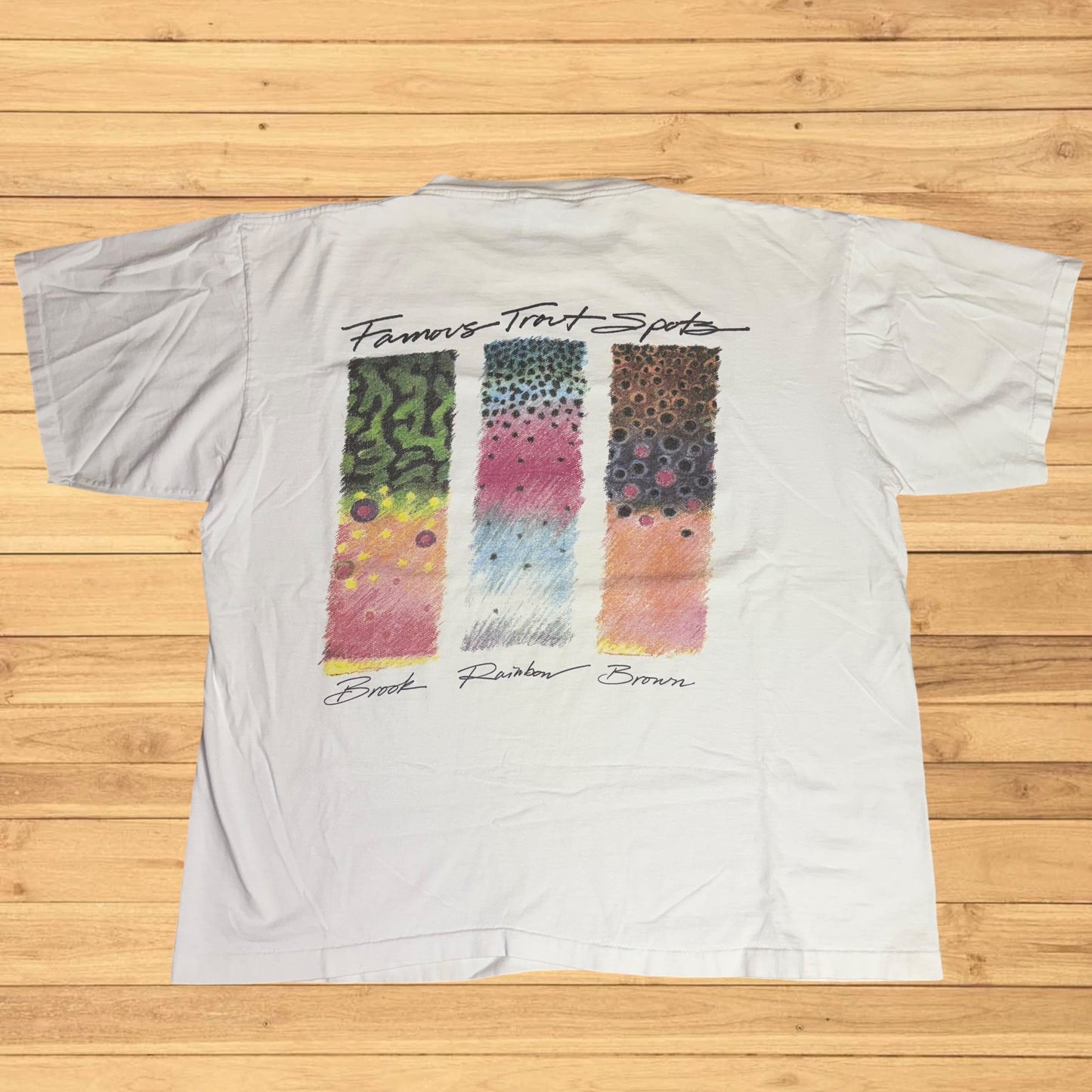 White t-shirt with colorful pattern design on a wooden surface