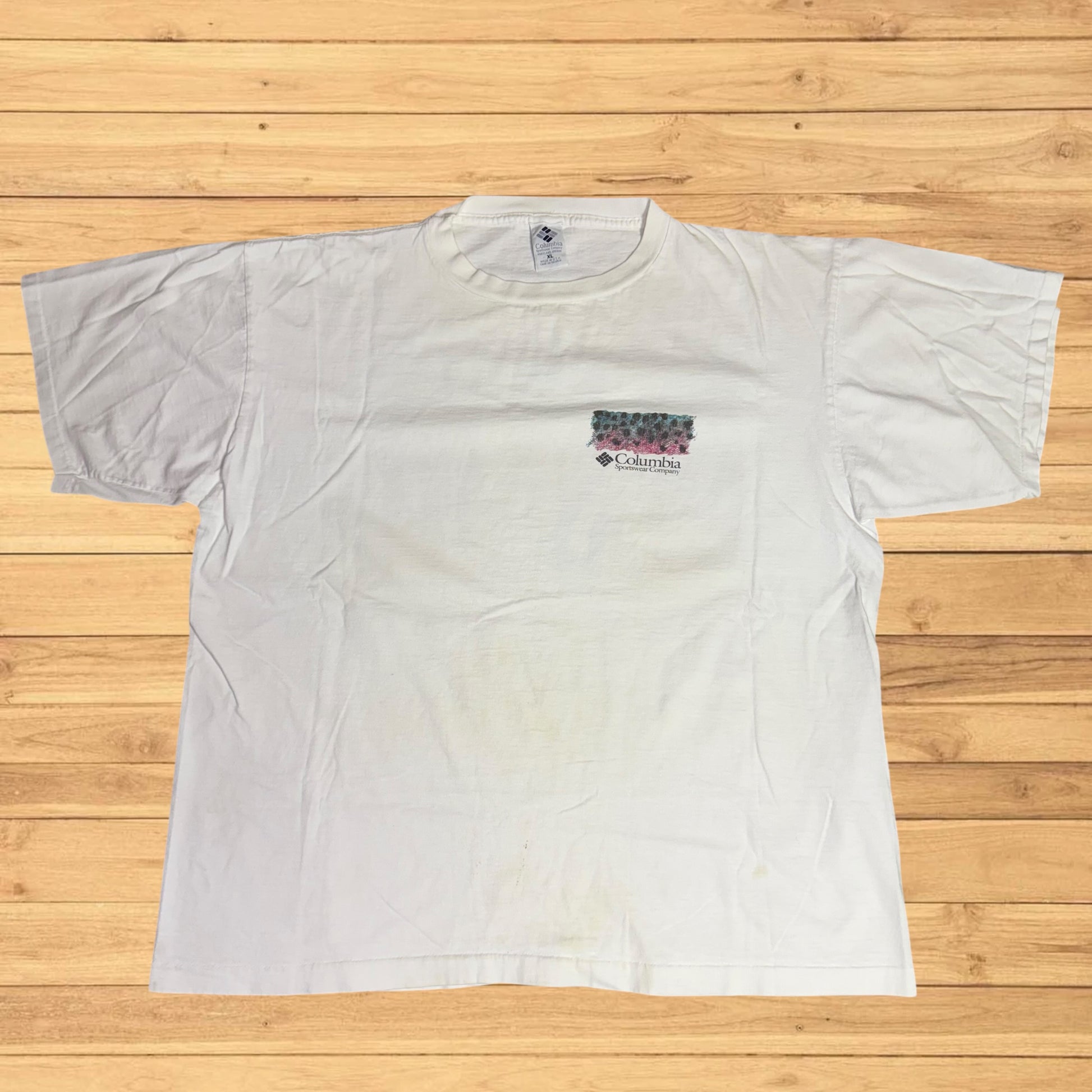 White t-shirt with Columbia logo on a wooden surface