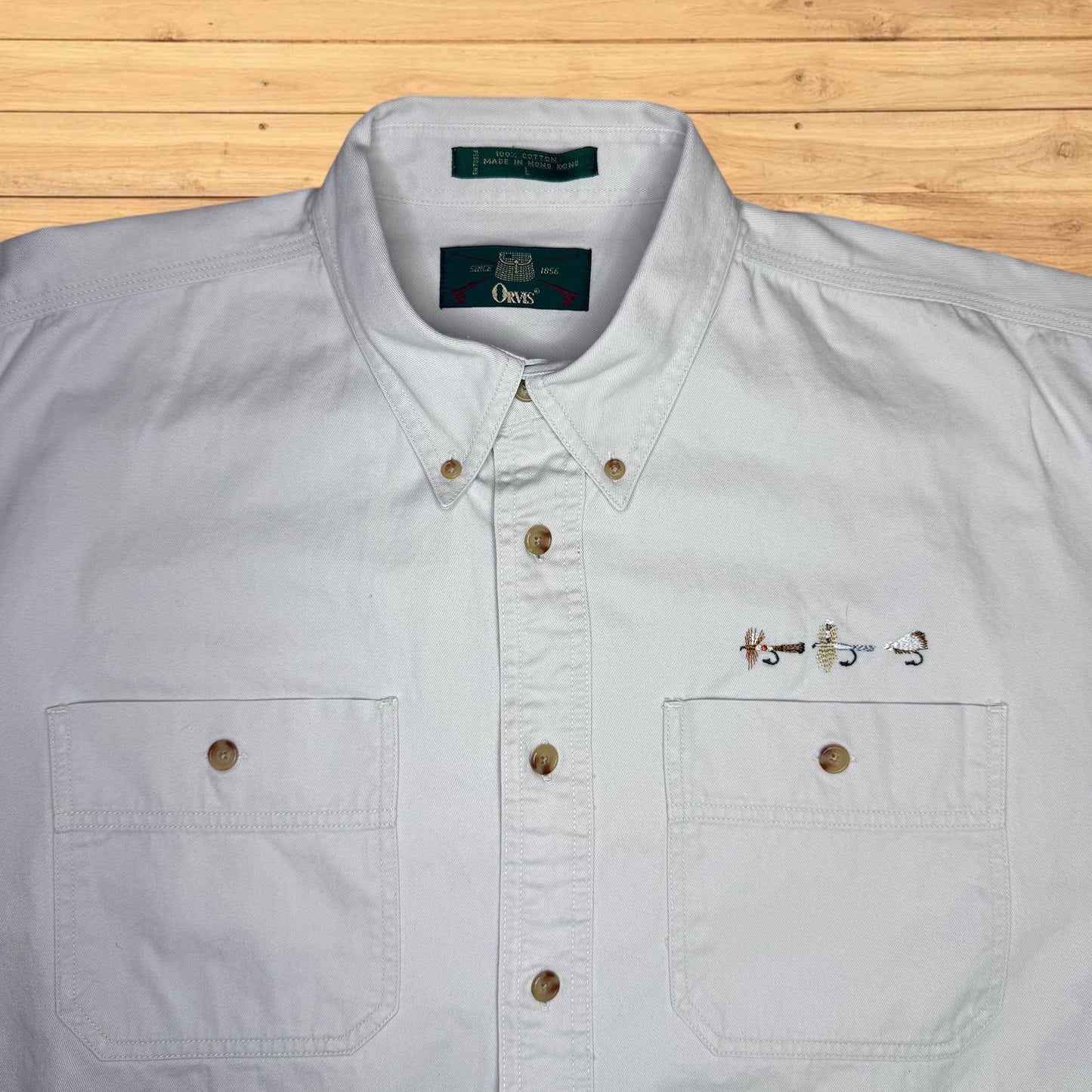Light gray button-up shirt with a brand label on a wooden surface