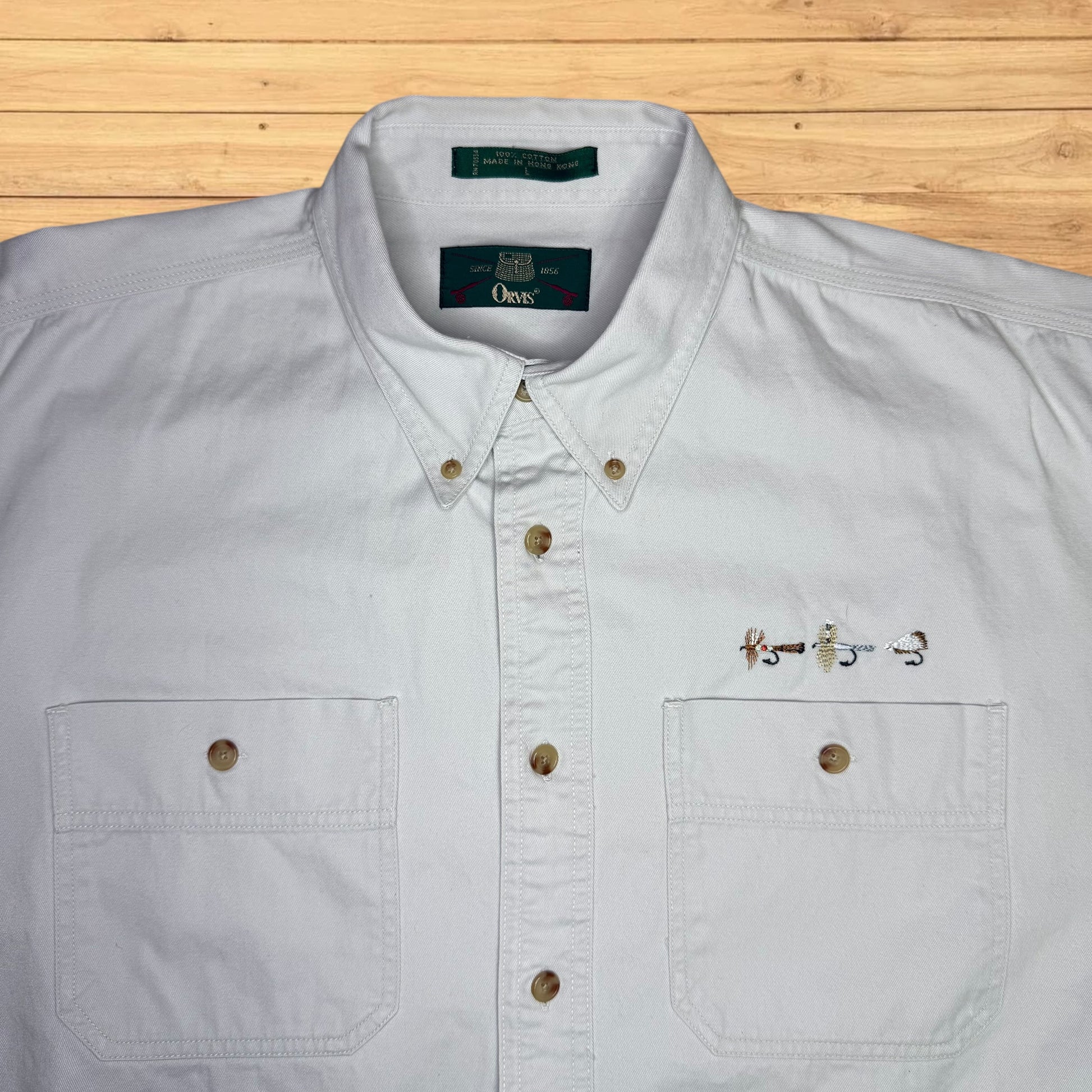 Light gray button-up shirt with a brand label on a wooden surface
